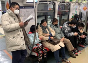 A man wearing a mask reads on the subway in Beijing, China January 21, 2020. REUTERS/Tingshu Wang
