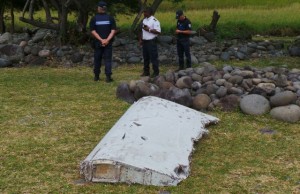 French gendarmes and police stand near a large piece of plane debris which was found on the beach in Saint-Andre, on the French Indian Ocean island of La Reunion, in this picture taken July 29, 2015. The Malaysian Prime Minister said early on Thurday August 6, 2015 the Boeing 777 barnacle-covered debris, a 2-2.5 metre (6.5-8 feet) wing surface known as a flaperon and discovered in the Indian Ocean island of Reunion was confirmed as coming from missing flight MH370 the first real breakthrough in the search for the plane that disappeared 17 months ago. A French deputy prosecutor said in Paris August 5, 2015 that experts examining a piece of debris that washed up on Reunion Island have reached a "very strong presumption" that it comes from a missing Malaysian jetliner but their finding still needs to be confirmed. Picture taken July 29, 2015. REUTERS/Zinfos974/Prisca Bigot/Files