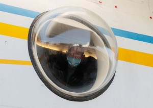 A man wearing a protective mask looks through a plane window, as Ukrainian medical personnel depart for Italy amid the coronavirus (COVID-19) pandemic, at an airport in Kiev, Ukraine April 4, 2020. REUTERS/Gleb Garanich TPX IMAGES OF THE DAY