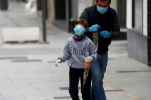 A man and a child wear protective face masks as they walk along the empty La Bola street, after restrictions were partially lifted for children for the first time in six weeks, during the coronavirus disease (COVID-19) outbreak in Ronda, Spain, April 26, 2020. REUTERS/Jon Nazca